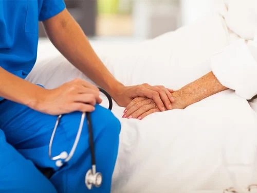 A person holding someone's hand in a hospital bed